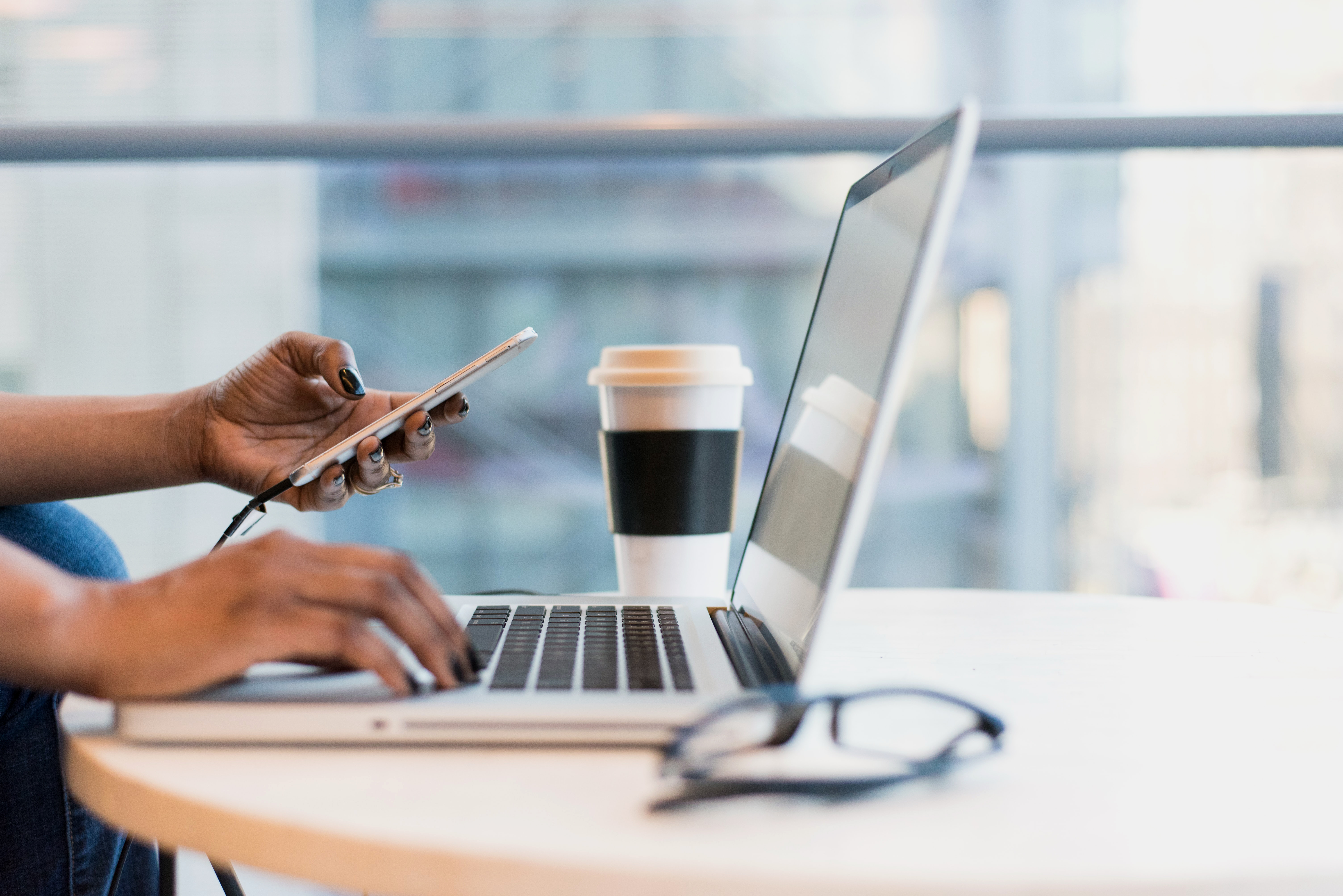 Person working on laptop with phone and notebook